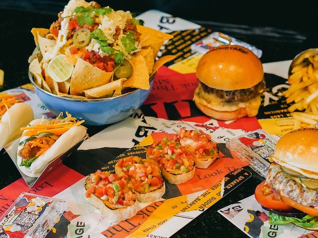 Table with fast food menu beef burger, sweet potato fries, nachos, slider, bruschetta, burrito
